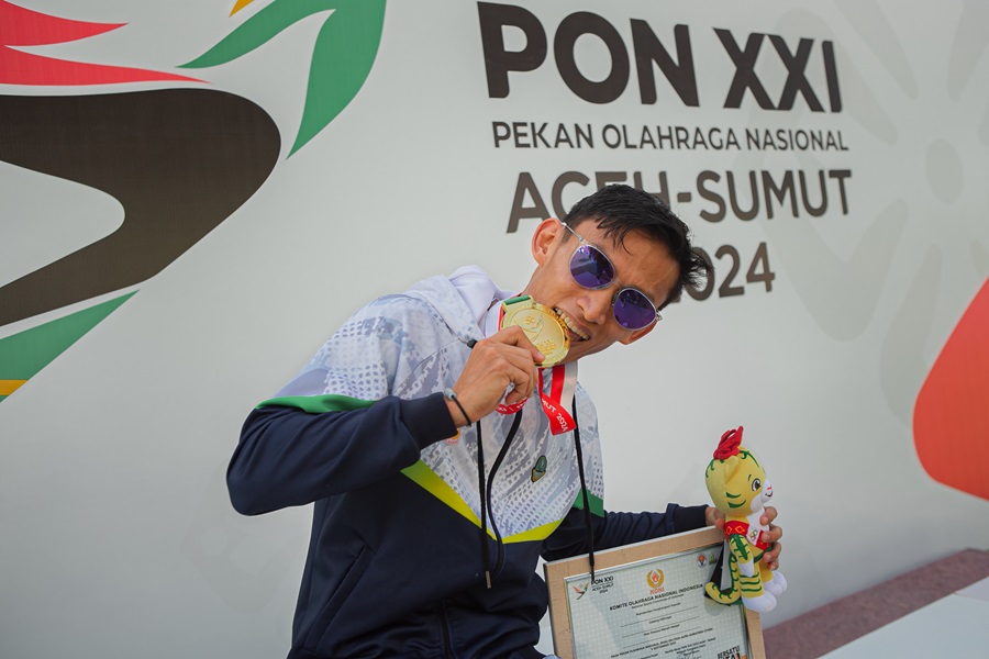 Atlit Jawa Barat Hendro Putra gigit medali emas yang diperolehnya setelah menjasi finisher tercepat dengan catatan waktu 1:35:50.00 pada event jalan cepat 2000m putra PON XXI ACEH-SUMUT, di Stadion Madya Sena Sumatra Utara, Deliserdang, rabu (18/9/2024). PB PON XXI Sumut / Agatha Capri